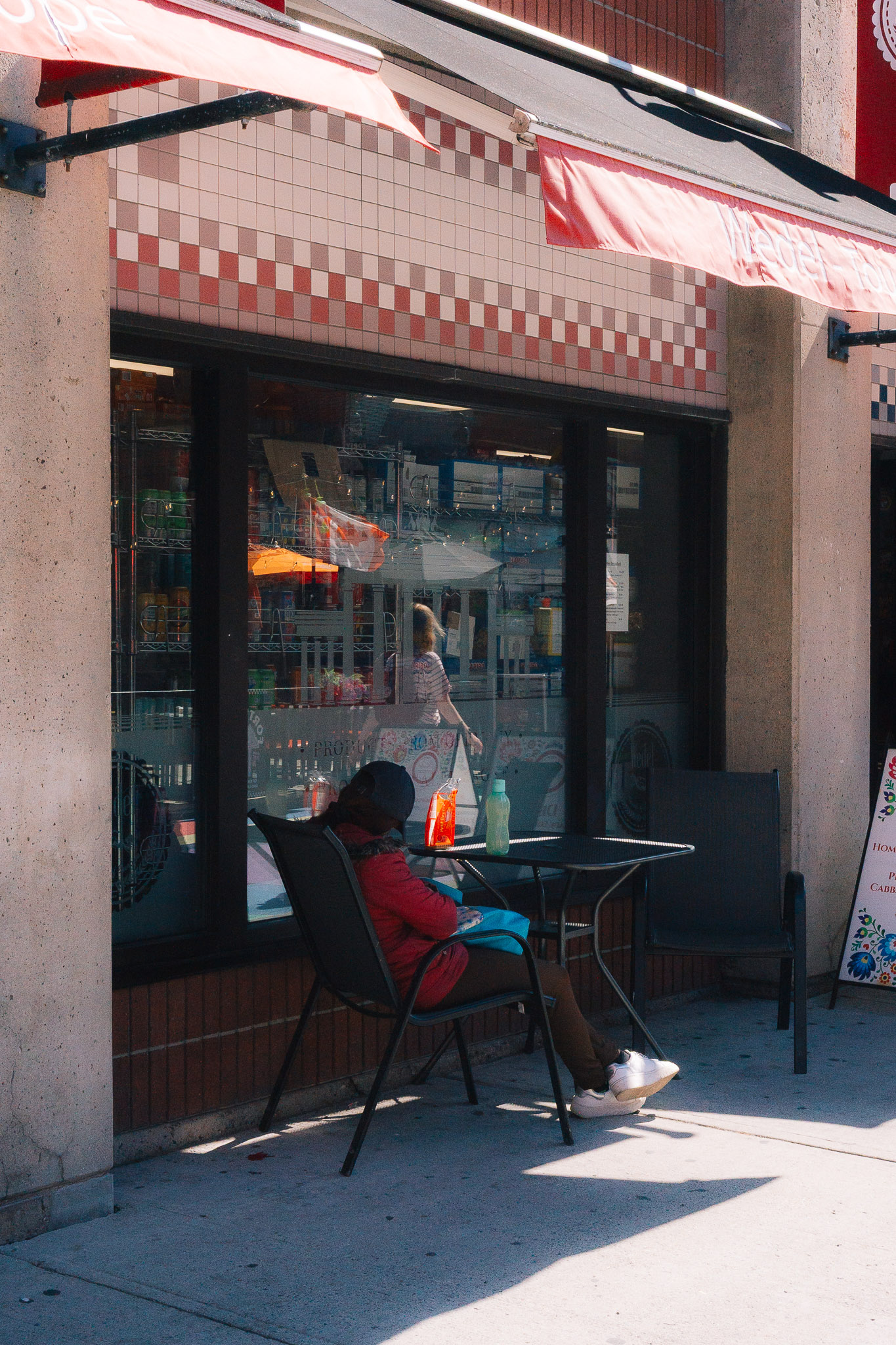 Woman in a red top sitting at a café table on a sunny sidewalk