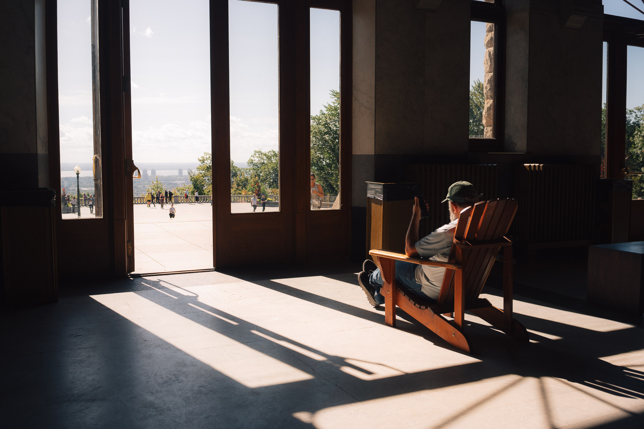 Man in a wooden chair in a dim hall, long bars of sunlight falling across the floor