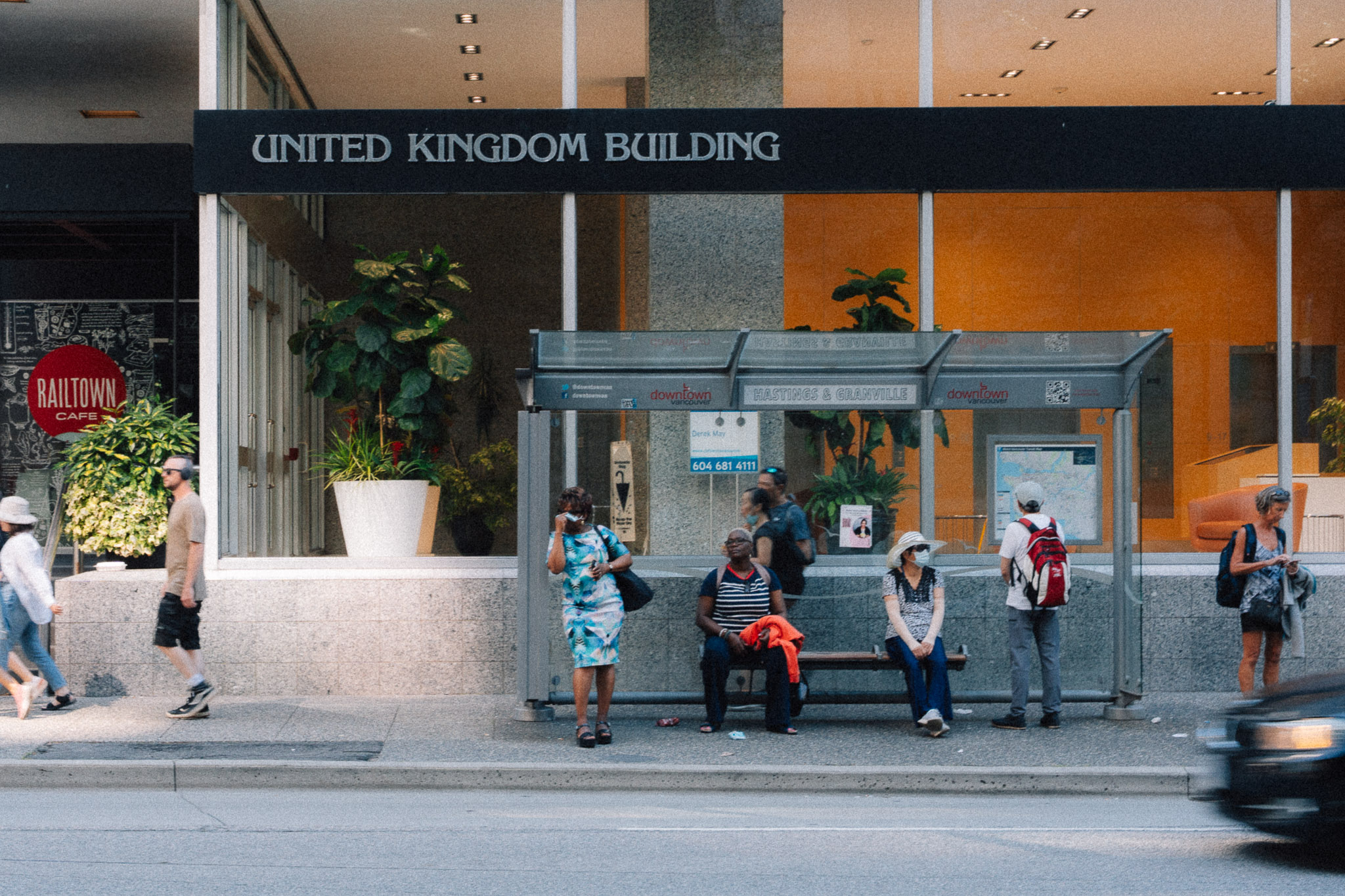 People waiting at a bus shelter in front of the United Kingdom Building