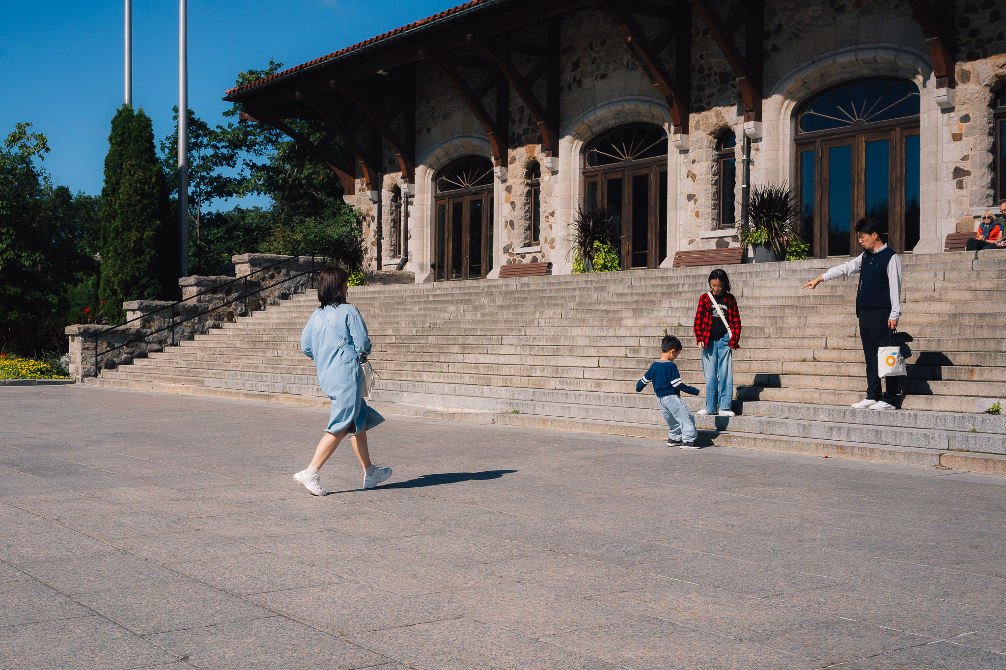 Children playing on wide stone stairs in front of a historic hall while a woman walks past