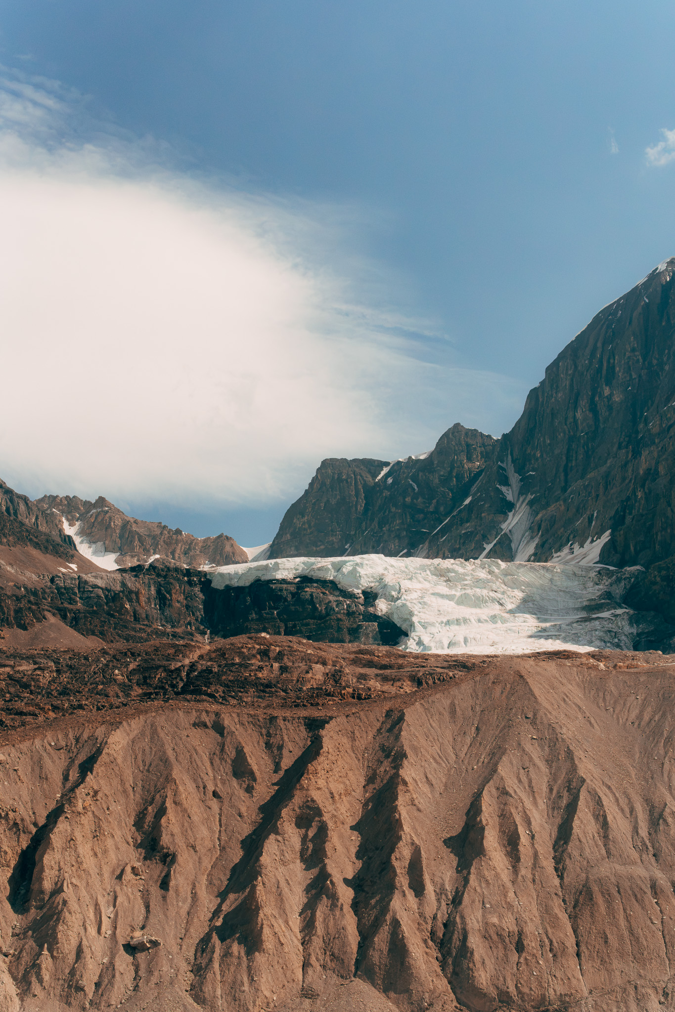 Glacier tongue spilling between cliffs above bare moraine ridges