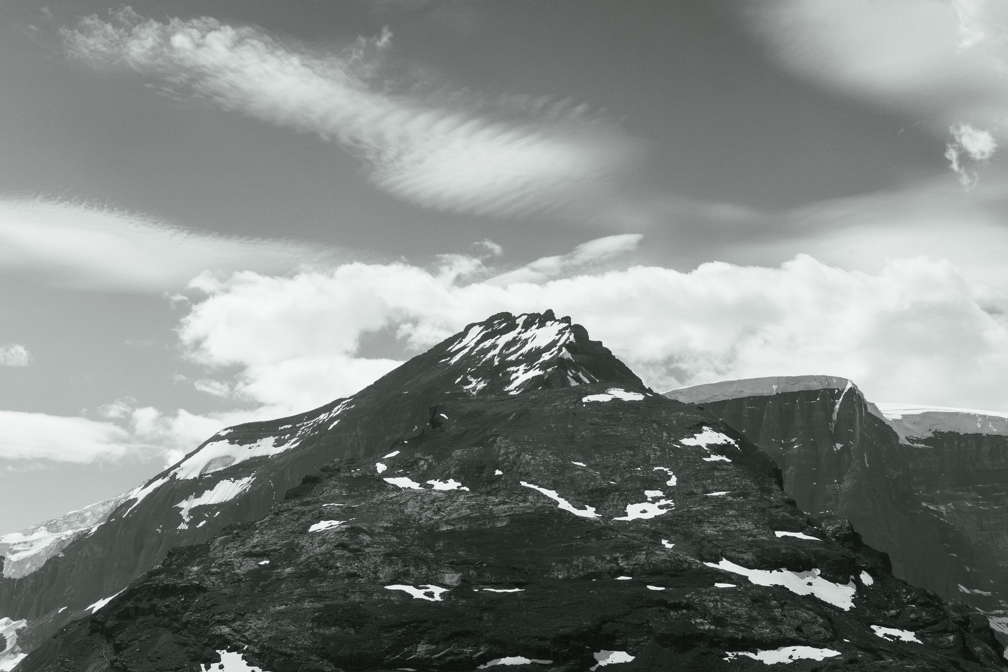 Black and white peak dusted with snow under streaked cloud
