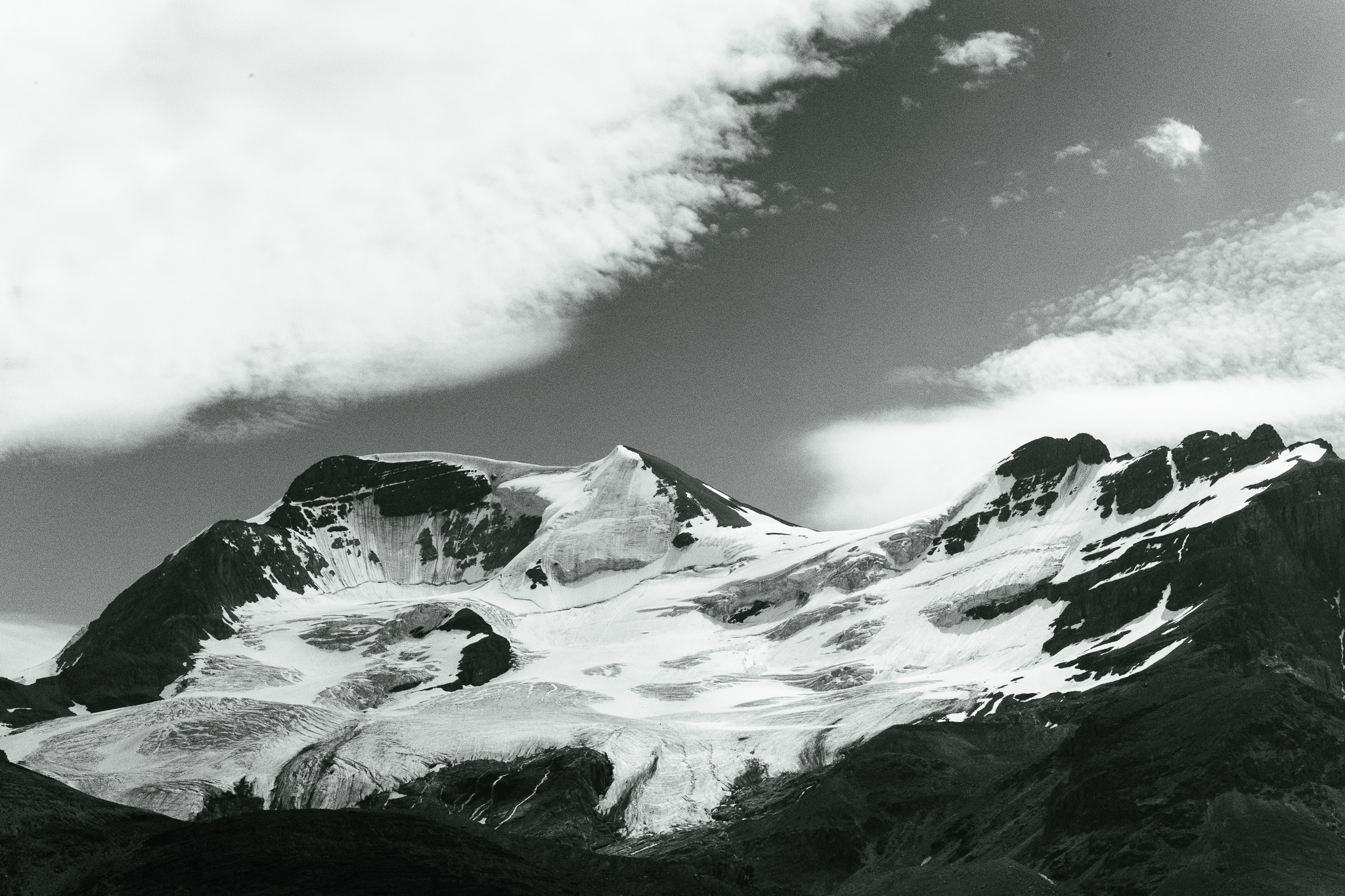 Black and white snowfield and glacier below a broad summit