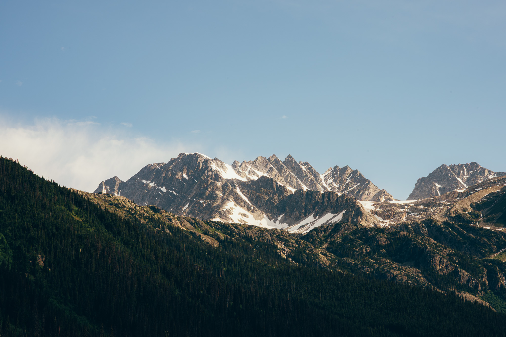 Jagged snow-streaked peaks above a dark forested ridge