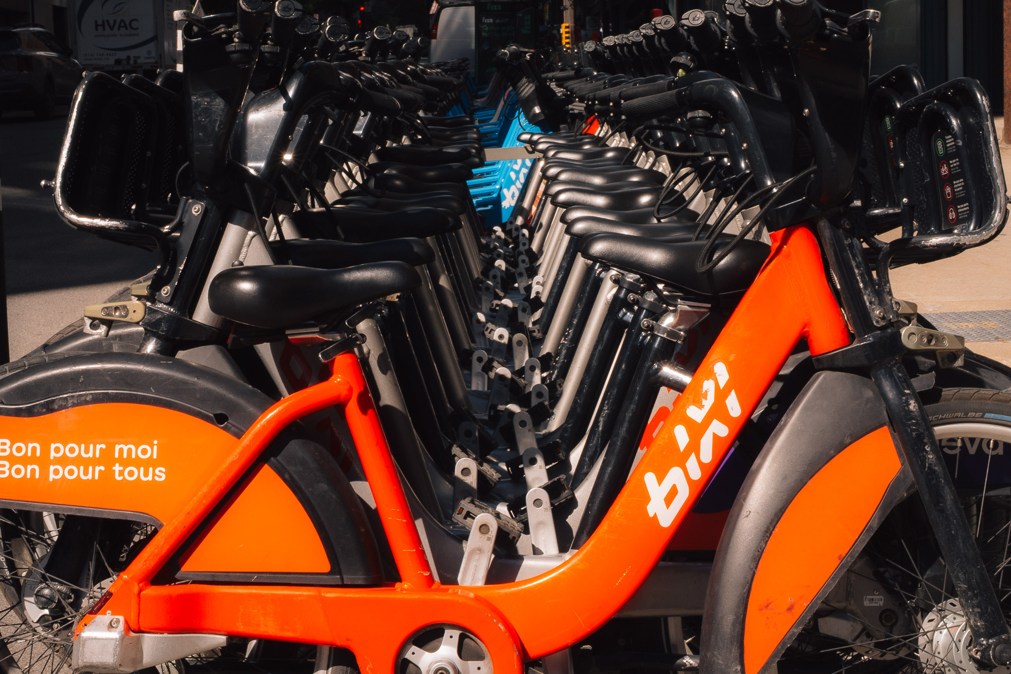 Orange-red BIXI bike at the front of a long row of docked bikes