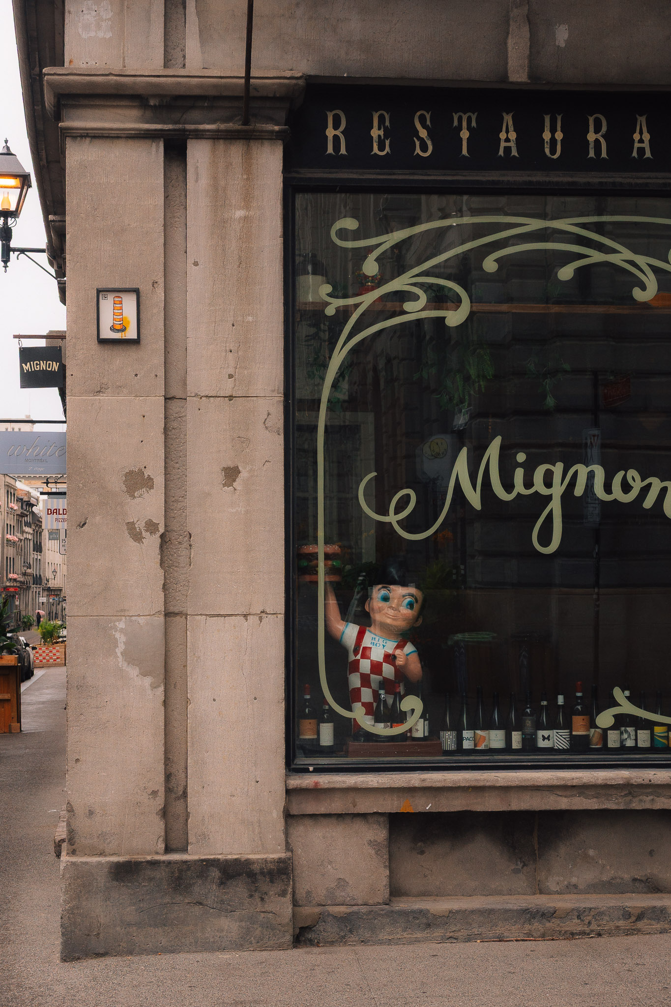 Restaurant window with gold lettering, a small figure in red and white checks standing behind the glass